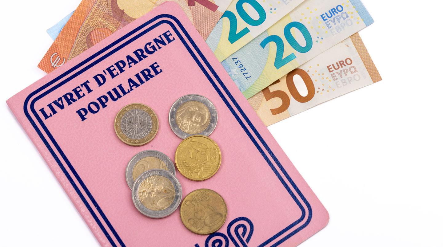 Gros plan sur une calculatrice moderne et un smartphone posés sur une surface blanche épurée, avec une main en arrière-plan effectuant un calcul